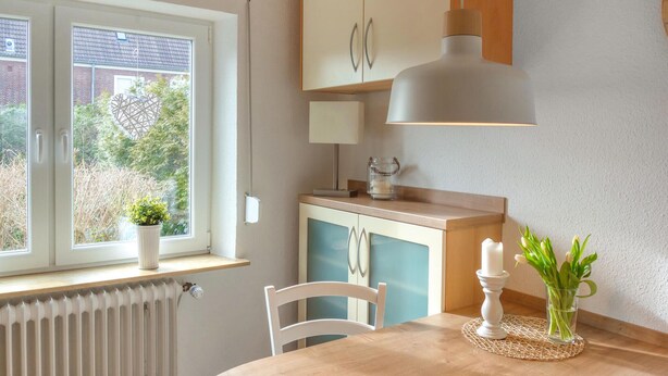 Eine Küche mit Fenster, Heizkörper, Tisch mit Kerze und Blumenvase.