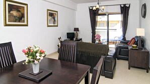 A dining area with a table, chairs, and a vase of flowers. There is a sofa and a TV in the background. - Casa Gloria, easy walk to city centre (Lagos)