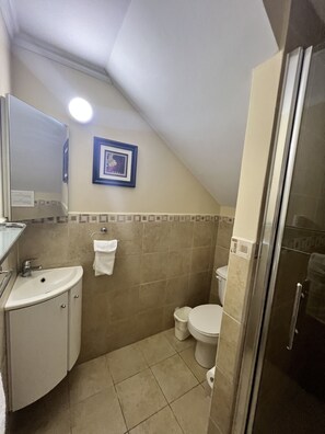 A small, compact bathroom with a sink, toilet, and shower.