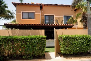 A two-story building with a flat roof, a balcony, and a gate.