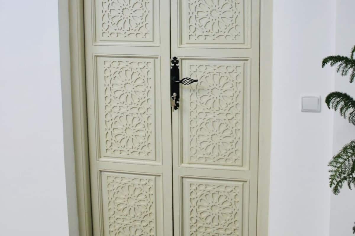 A white door with intricate floral carvings and a small window above it.