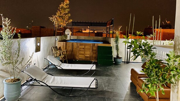 A rooftop terrace with lounge chairs, a hot tub, and a wooden deck. - Dar Riad Jomana (Marrakech)