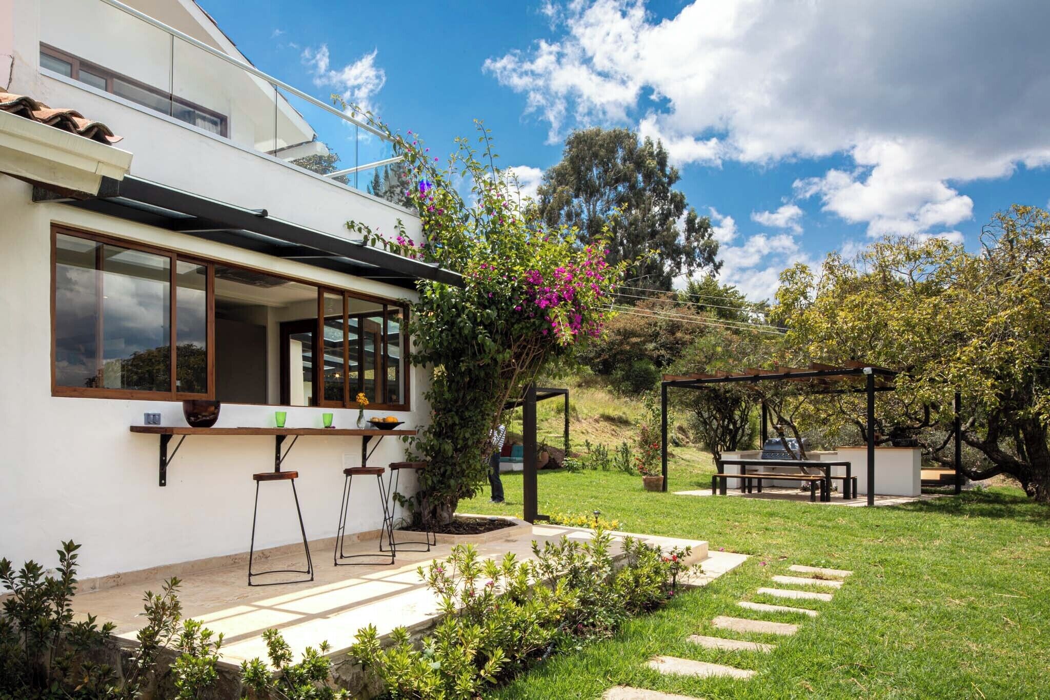 Een modern huis met een patio, een pergola en een barbecue.