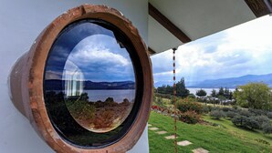 Ein rundes Fenster mit Blick auf einen See und Berge.