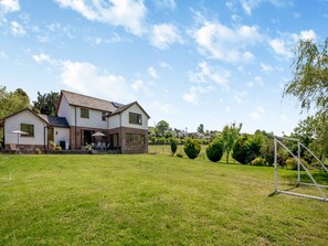 Een huis met twee verdiepingen, een terras en een verzorgd gazon.