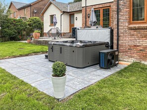Een wellnessruimte met een bubbelbad, buitenzitplaatsen en een kleine potplant.