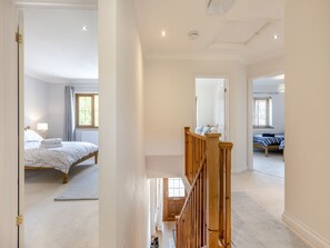 Een ruime slaapkamer met een groot bed, een houten trap en uitzicht op een andere kamer.