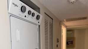 Un área de lavandería con lavadora y secadora Whirlpool, una puerta con interruptor de luz y piso de baldosas.