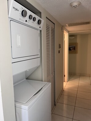 Un área de lavandería con lavadora y secadora Whirlpool, una puerta con interruptor de luz y piso de baldosas.