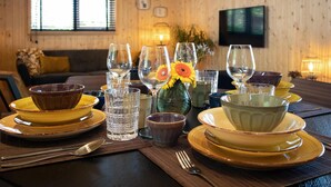 Un tavolo da pranzo apparecchiato con piatti gialli, bicchieri trasparenti e un vaso con fiori.