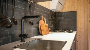 Una cucina moderna con lavello in acciaio inossidabile, piano cottura a gas e tagliere in legno.