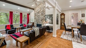 A spacious living room with a stone accent wall, leather furniture, and a dining area with a wooden table and chairs.