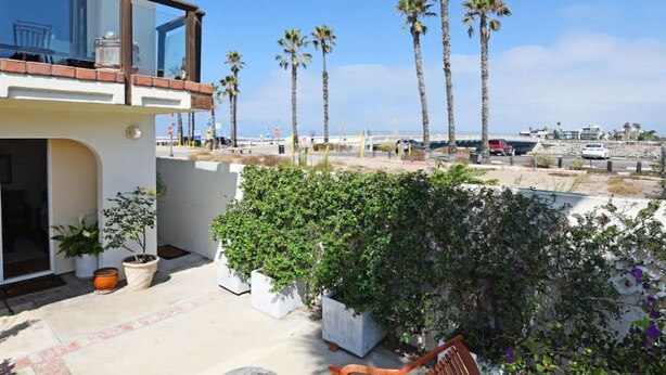 A balcony with a view of palm trees and a beach.