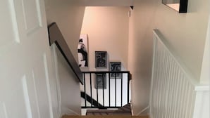 A staircase with a wooden floor, white walls, and black railings. - Cozy Loft for 2- Steps from Village of Pittsford (Pittsford)