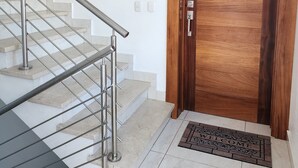Una escalera con barandilla de metal que lleva a una puerta de madera con el número 2 encima.