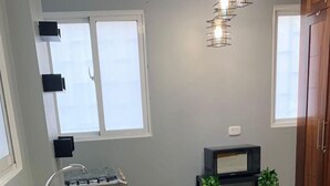 Una cocina con encimera de granito, pileta de acero inoxidable y comedor con mesa de vidrio.