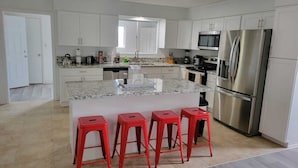 A modern kitchen with white cabinets, a stainless steel refrigerator, a microwave, and a granite countertop. - Family Ranch in pahrump (Pahrump)