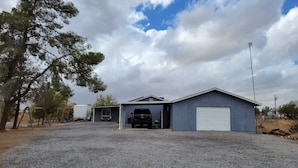 A single-story building with a garage, a covered area, and a small adjacent structure. - Family Ranch in pahrump (Pahrump)