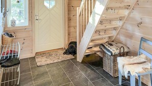 Ein Holzinnenraum mit einer Tür, einem Hund, einem Stuhl, einem Korb und einem kleinen Tisch.