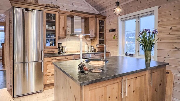 Eine Holzhütte mit einer Küche, die einen Edelstahl-Kühlschrank, Holzschränke, eine Granitarbeitsplatte und ein Fenster mit Aussicht besitzt.