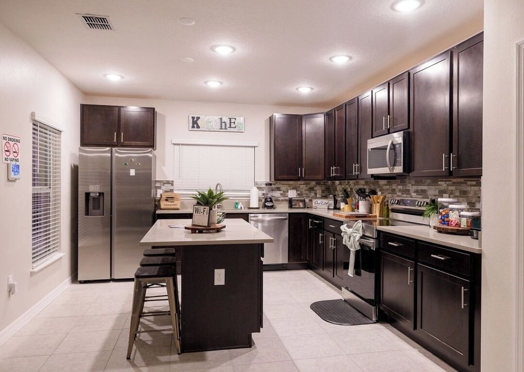 A modern kitchen with dark cabinets, stainless steel appliances, and a central island.