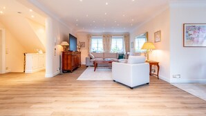 A spacious living room with a sofa set, a wooden cabinet, and a TV. - House Lucia, Whg. 01 - House Lucia (Sylt)