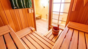 A sauna room with wooden benches and a wooden bucket. - House Lucia, Whg. 01 - House Lucia (Sylt)