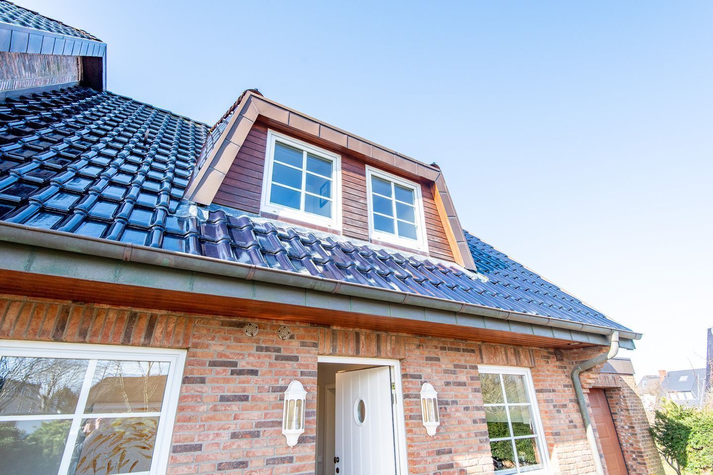 A two-story house with a sloped roof, a brick facade, and a small attic window.