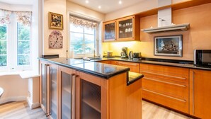 A modern kitchen with wooden cabinets, a central island, and a built-in microwave. - House Lucia, Whg. 01 - House Lucia (Sylt)