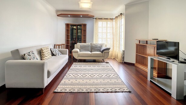 A modern living room with a sofa, a coffee table, a TV stand, and a wooden bookshelf. - Milagres Apartment by Atlantic Holiday (Machico)
