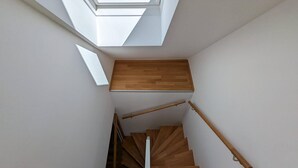 A modern staircase with wooden steps and handrails, leading to a landing with a skylight above. - Apartment in Mariazell Near Ski Slopes (Mariazell)