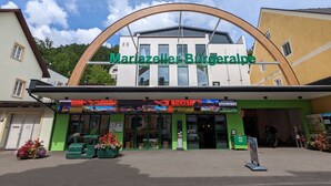 A restaurant named Mariazeller Burgerpalpe with a green facade, outdoor seating with flower pots, and a clear sky. - Apartment in Mariazell Near Ski Slopes (Mariazell)