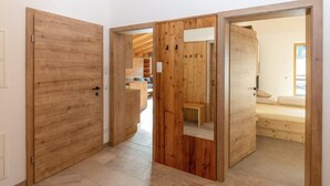 A hallway with wooden doors leading to a room with a bed and a bench. - Spacious Family Flat in Kleinarl (Kleinarl)