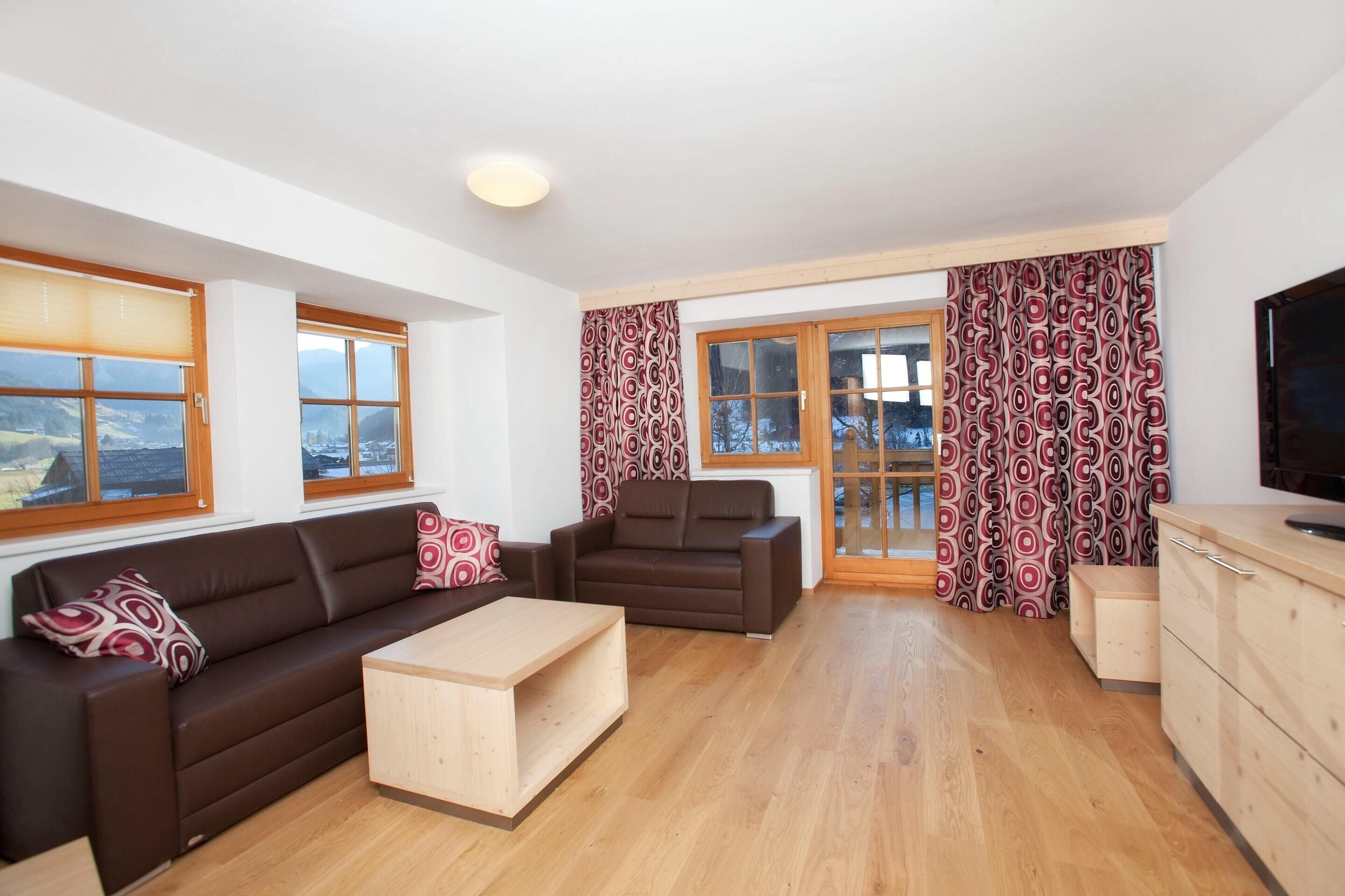 Ein modernes Wohnzimmer mit einem braunen Sofa, einem Holztisch und einem Fernseher auf einer Holzkommode.