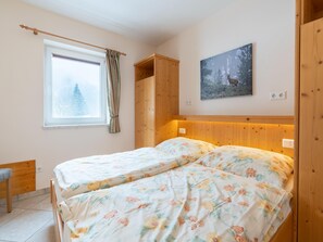 A bedroom with two beds, a wooden wardrobe, a window with curtains, and a painting of a deer. - Holiday Home in Hollersbach im Pinzgau (Hollersbach im Pinzgau)