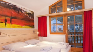 A hotel room with a large bed, a painting on the wall, and a view of a building through the window. - Apartment in Wald im Pinzgau Near Ski Slope (Wald im Pinzgau)