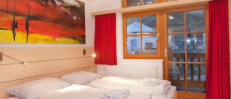 A hotel room with a large bed, a painting on the wall, and a view of a building through the window.