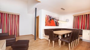 A modern dining area with a wooden table and chairs, a bench, and a red-striped curtain. - Apartment in Wald im Pinzgau Near Ski Slope (Wald im Pinzgau)