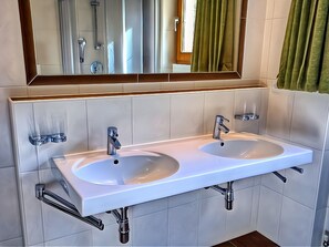Casa de banho moderna com duas pias, espelho e chuveiro.