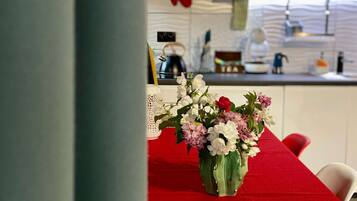 A dining table with a red tablecloth and a vase of flowers.