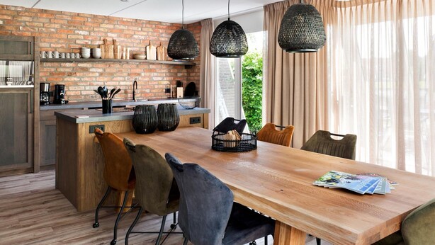 A modern kitchen with a brick wall, wooden beams, and pendant lights. - Luxury Holiday Home With Sauna in Vlagtwedde (Vlagtwedde)