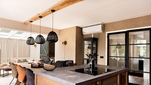 A modern kitchen with a large island, pendant lights, and a view to the dining area. - Luxury Holiday Home With Sauna in Vlagtwedde (Vlagtwedde)