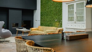 A modern living room with a black wall, a green vertical garden, a beige sofa, wicker chairs, a coffee table, and a cabinet with glassware. - House in Leenderstrijp Near Leenderbos Trails (Leende)