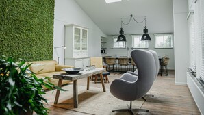 A spacious living area with a high ceiling, a green wall, and a dining area with modern furniture. - House in Leenderstrijp Near Leenderbos Trails (Leende)