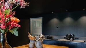 A modern kitchen with a wooden countertop, a vase with flowers, and kitchen utensils. - House in Leenderstrijp Near Leenderbos Trails (Leende)