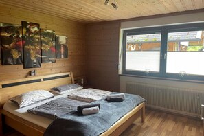Quarto com painéis de madeira, uma cama, obras de arte, uma janela e um radiador.