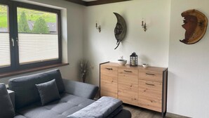 Een kamer met een grijze bank, een houten kast en decoratie aan de muur.