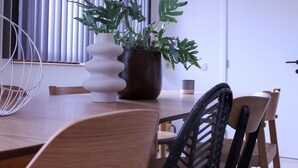 A modern dining area with a wooden table, a white vase, a potted plant, and a black chair. - Retreat Near Maasmechelen (Lanaken)