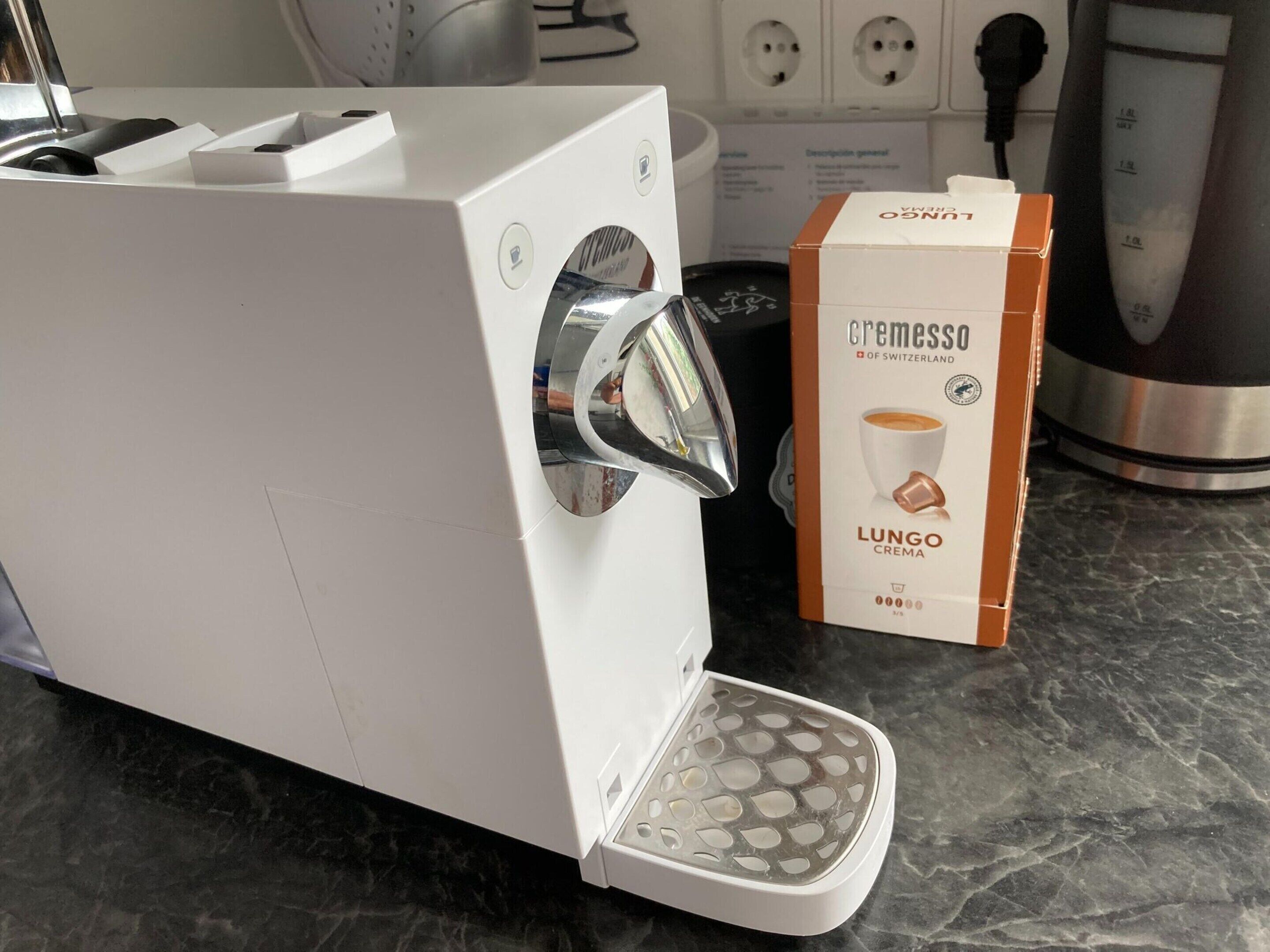 A coffee machine with a box labeled "Lungo Crema" on a kitchen counter.