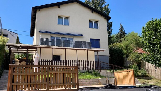 A two-story house with a balcony, a wooden fence, and a swimming pool. - Apartment in Mauerbach Near Vienna With Pool (Mauerbach)